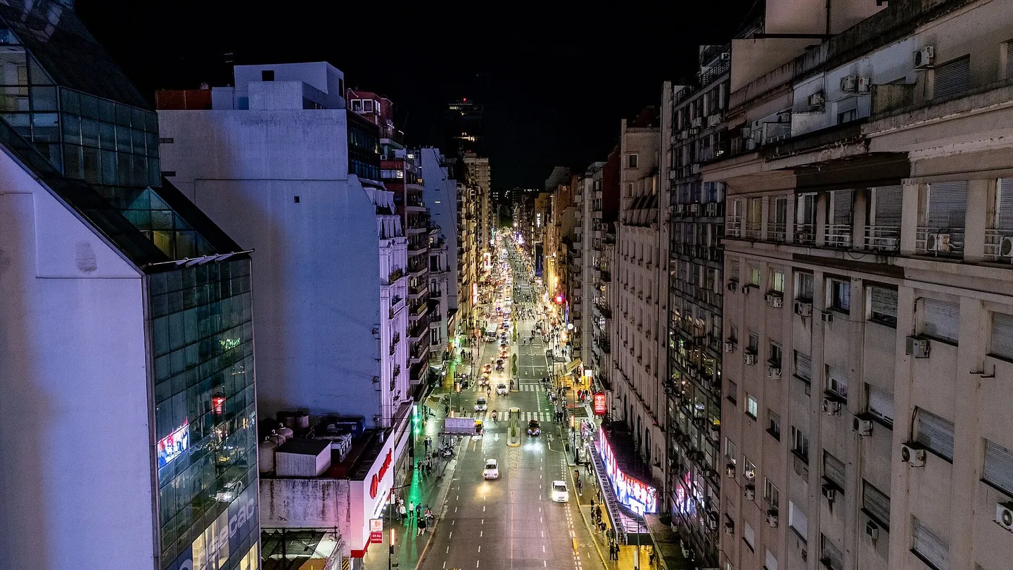 Vista aérea noturna do cruzamento da Avenida 9 de Julio com a Avenida Corrientes, em Buenos Aires, com o Obelisco iluminado
