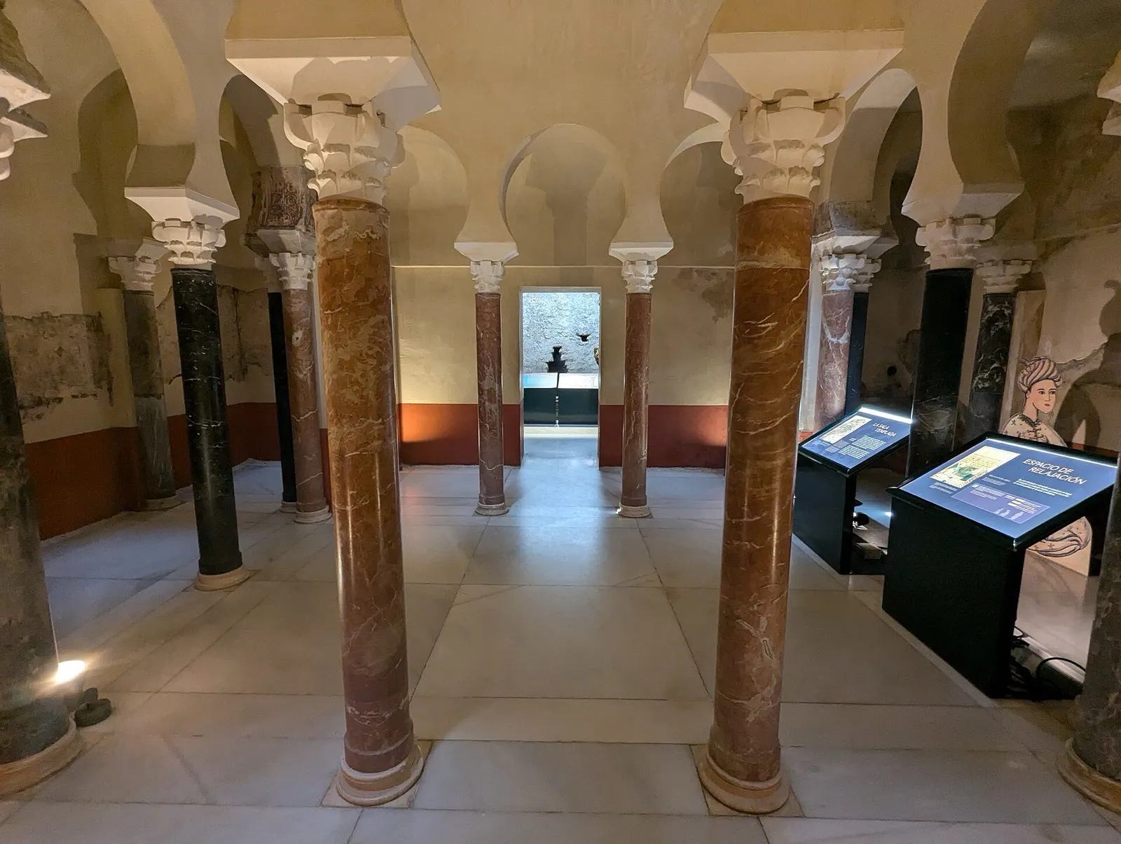 Sala dos banhos califais de Córdoba, com colunas e arcos de ferradura e painéis do museu
