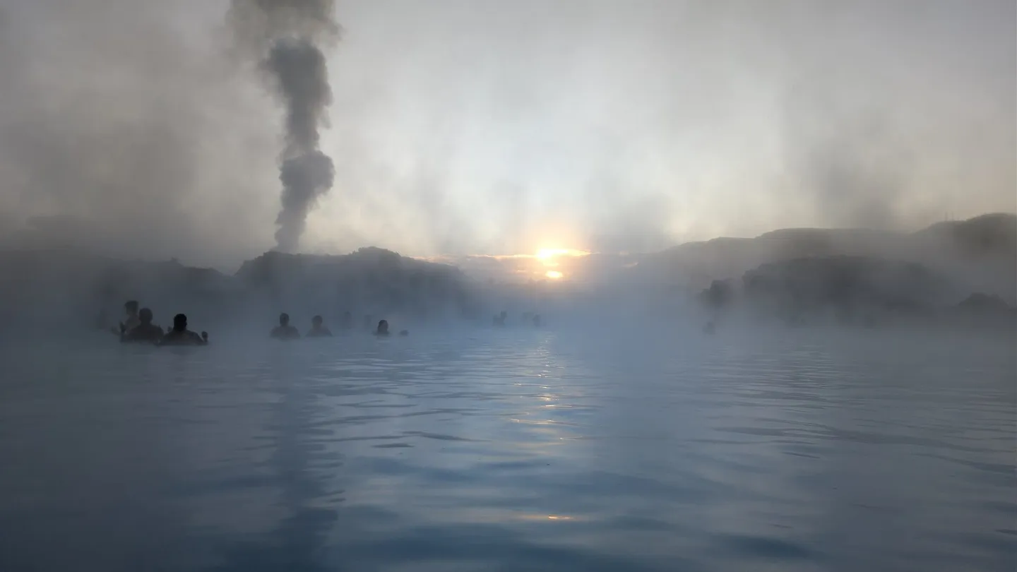 Nascer do sol na Blue Lagoon, na Islândia, com vapor sobre a água azul-leitosa e banhistas ao longe