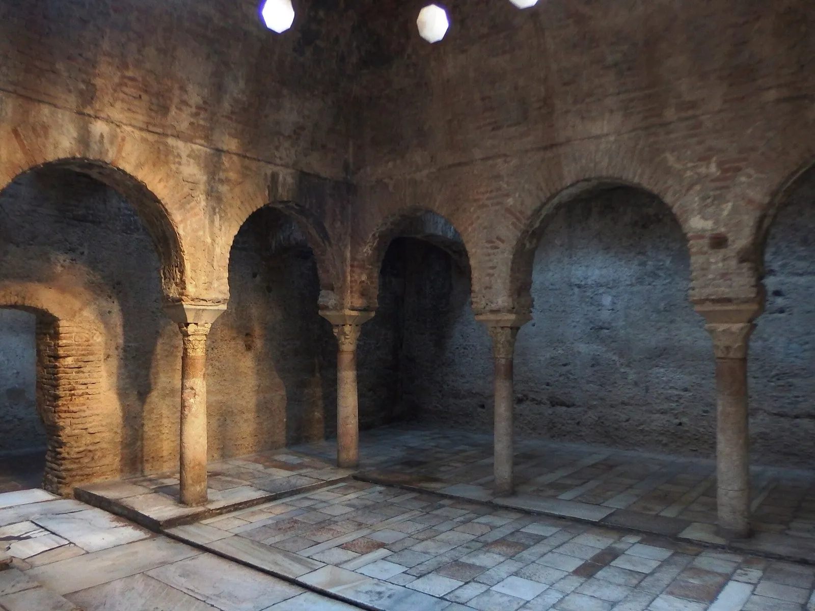 Sala morna do Bañuelo de Granada, com arcos de ferradura sobre colunas e piso de lajes de pedra