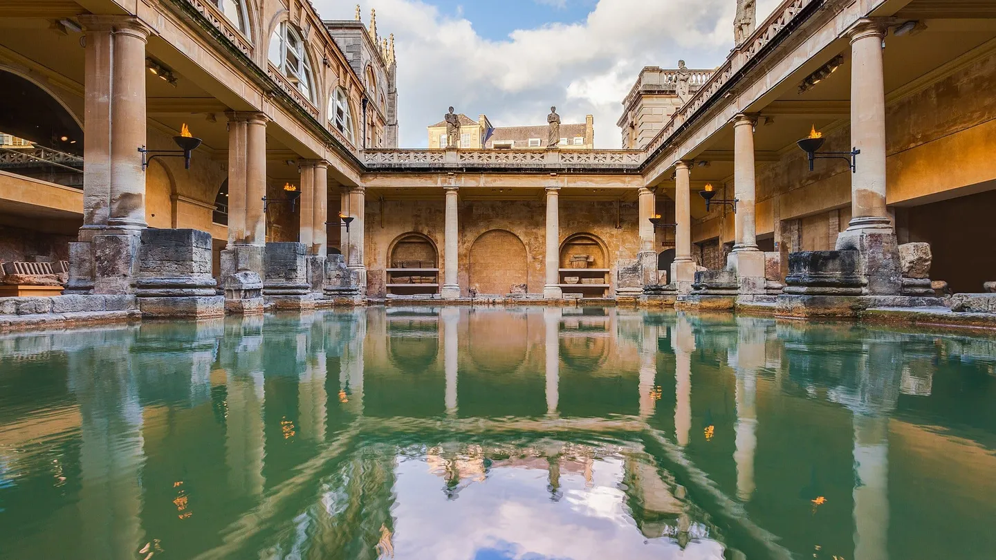 O Great Bath das Termas Romanas de Bath, na Inglaterra, com a piscina de água verde cercada por colunas e o piso superior do século XIX