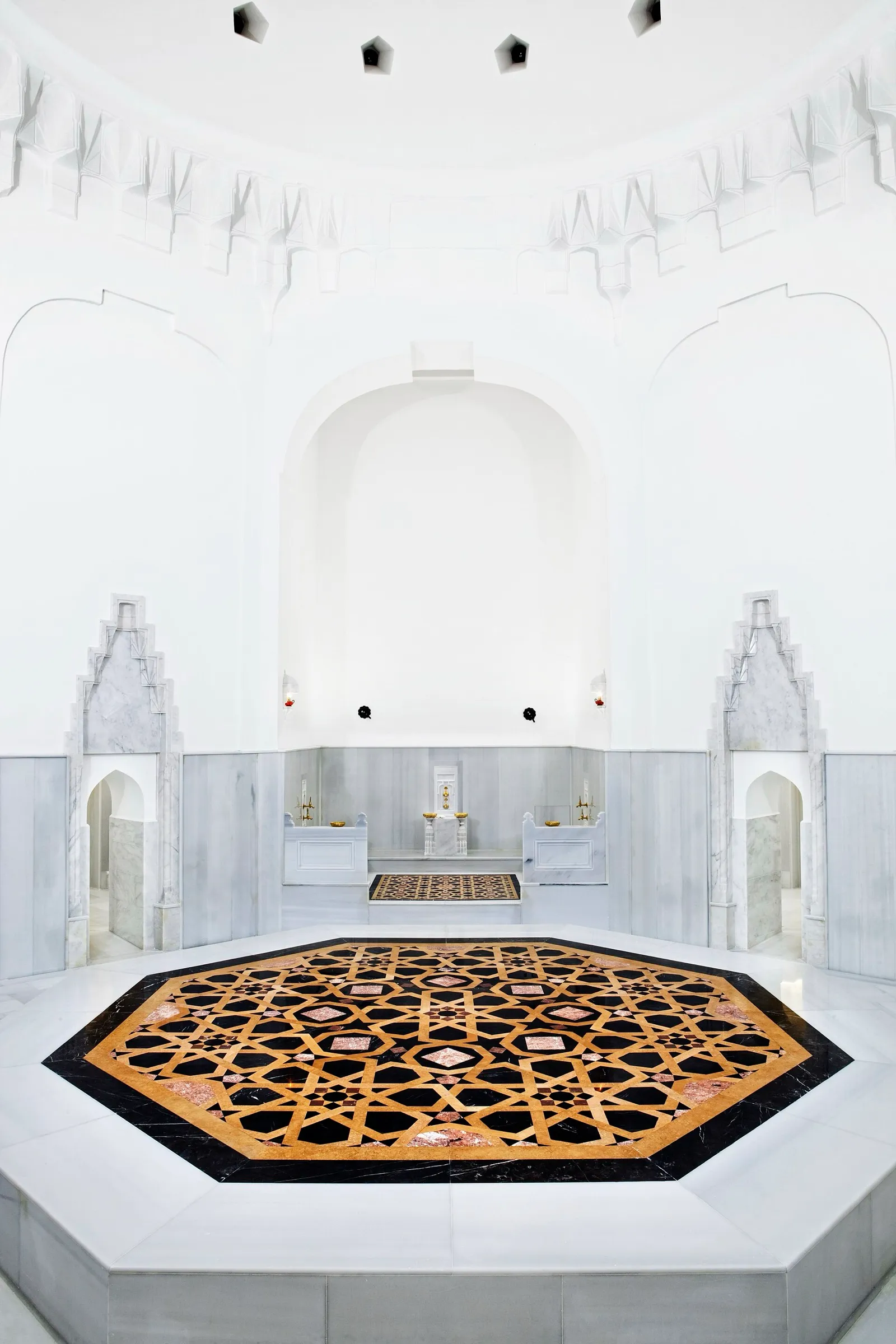 Sala quente do Hürrem Sultan Hamamı, em Istambul, com paredes de mármore branco, nichos de lavagem e uma plataforma octogonal de mármore com incrustações no centro