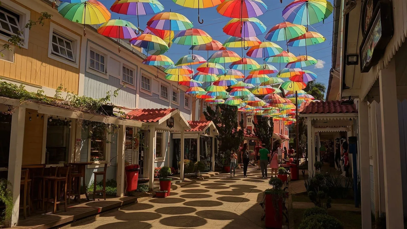 Rua de pedestres da Pequena Finlândia, em Penedo, coberta por guarda-chuvas coloridos suspensos