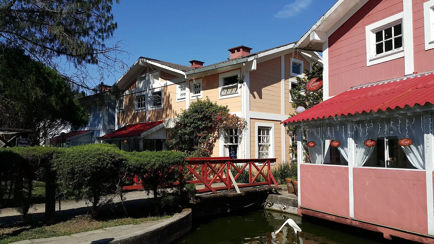 Ponte de madeira vermelha sobre um córrego entre casas de estilo finlandês na Pequena Finlândia, em Penedo, Itatiaia