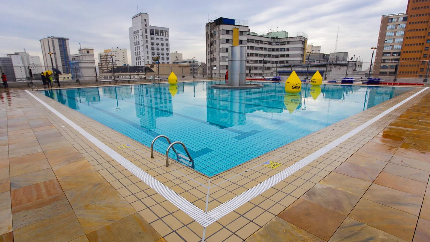 Piscina quadrada na cobertura do Sesc 24 de Maio, vazia no dia da inauguração, com boias amarelas e os prédios do centro de São Paulo ao fundo