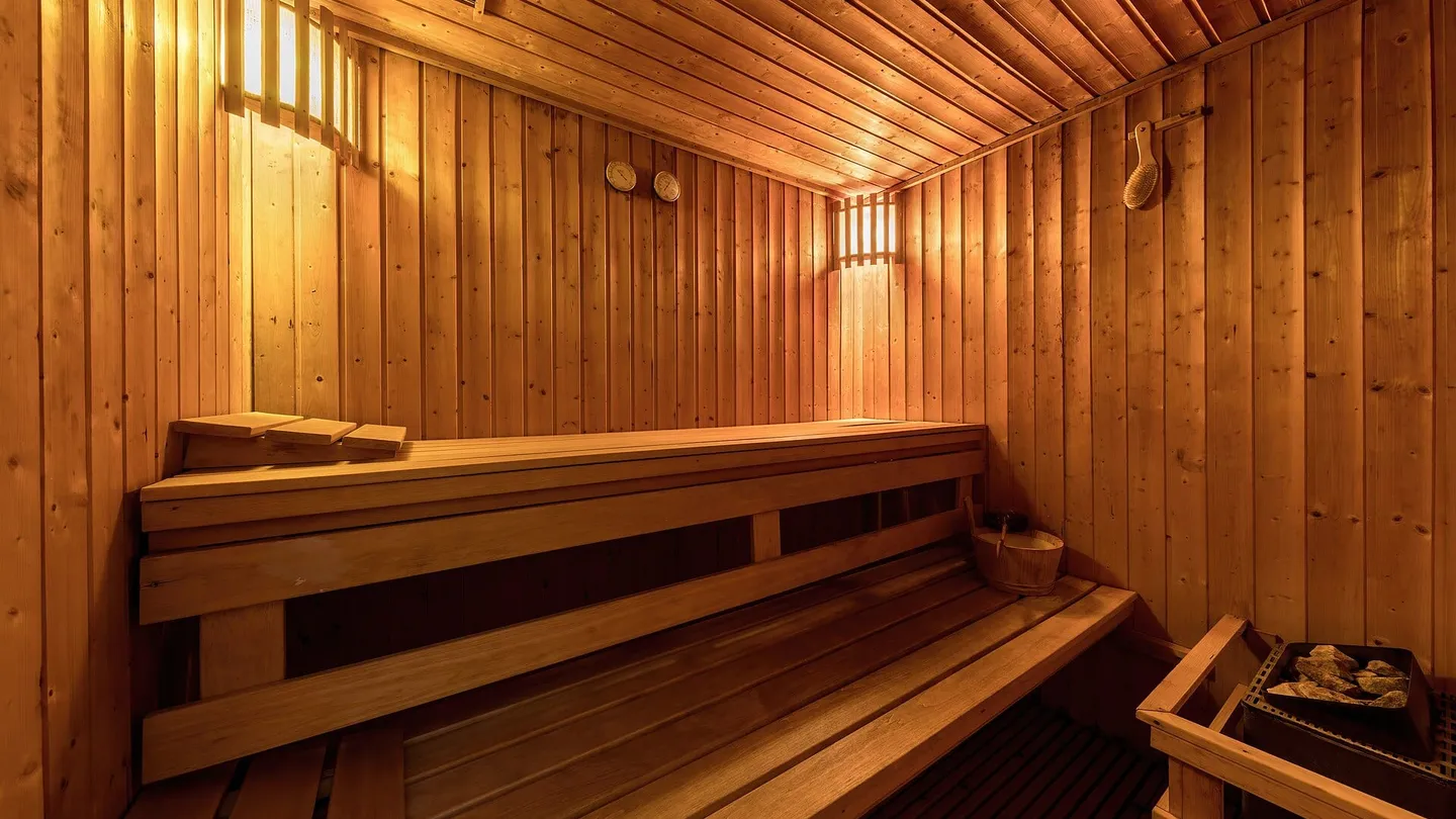 Interior de sauna revestida de madeira clara, com bancos em dois níveis e luz quente, em Luang Prabang, no Laos