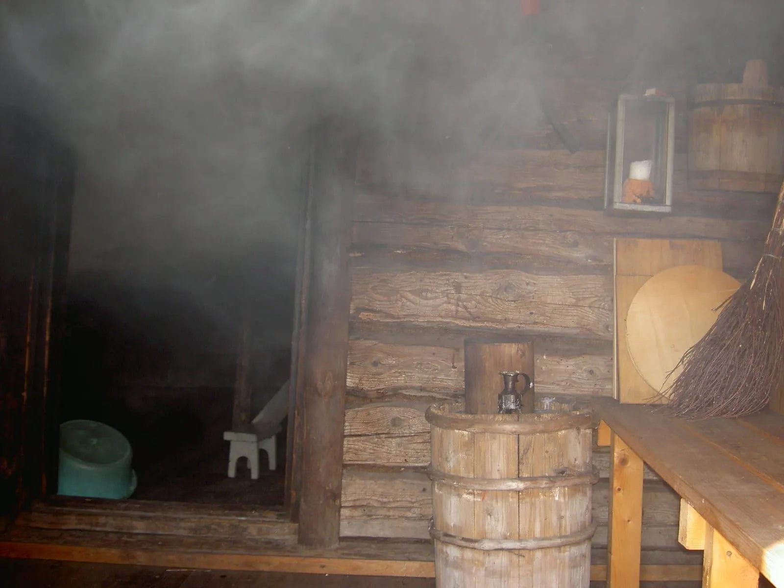Interior de uma sauna de fumaça finlandesa em Uusikaupunki, com vapor no ar, bancos de madeira e um balde