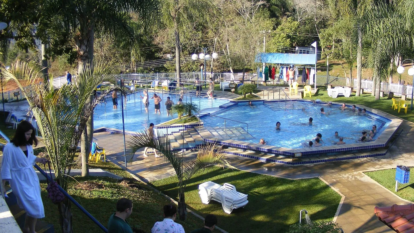 Piscina termal ao ar livre do Parque Termas de Piratuba, em Santa Catarina, entre palmeiras e mata, com banhistas na água